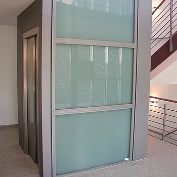 Glasaufzug mit silbernem Rahmen in einem modernen Gebäude.